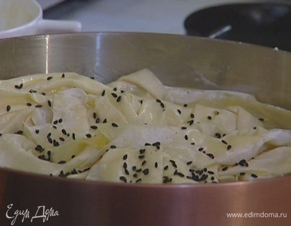 Пласты теста смазать оливковым маслом, уложить «морщинками» на начинку, проколоть вилкой и присыпать сверху кунжутным семенем.