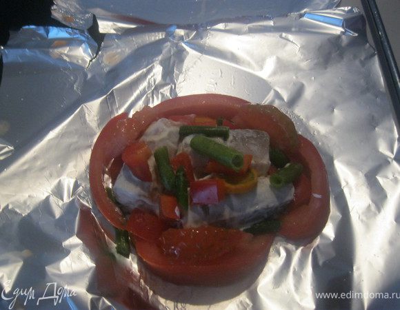 Нарезать морковь кружочками, перец квадратиками, помидоры дольками из них вырезать мякоть. Дольками помидора без мякоти обложить вокруг рыбы. Оставшиеся овощи выложить сверху и по бокам, посыпать солью,положить пару ложек сметаны и посыпать сыром.
