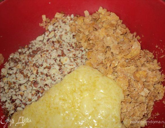 Орехи поджарить на сухой сковородке, остудить и измельчить в блендере ( не очень мелко ), кукурузные хлопья раскрошить с помощью скалки.Шоколад и масло растопить на водяной бане или в микроволновке и смешать с раздробленными орехами и хлопьями 