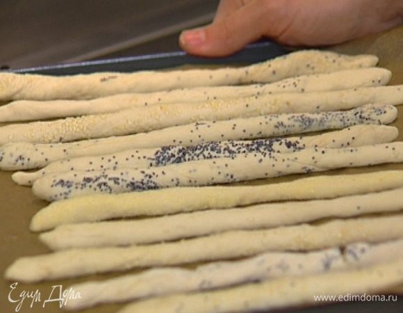 Когда тесто подойдет, разделить его на небольшие кусочки и скатать из них длинные тонкие палочки. Обвалять палочки в манке, маке или кунжуте.
