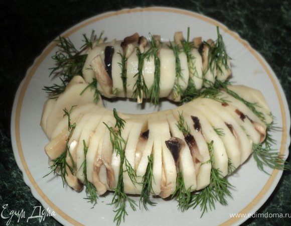 Очистить картофель, сделать глубокие надрезы поперек ( но не до конца ), что бы клубень раскрылся гармошкой.
Вложить в разрезы пластинки грибов и веточки укропа