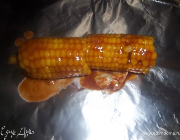 Сваренную кукурузу намазать масляной смесью. Соедините два кусочка кукурузы, плотно обернуть их фольгой и запекать в предварительно разогретой духовке 5 минут. 