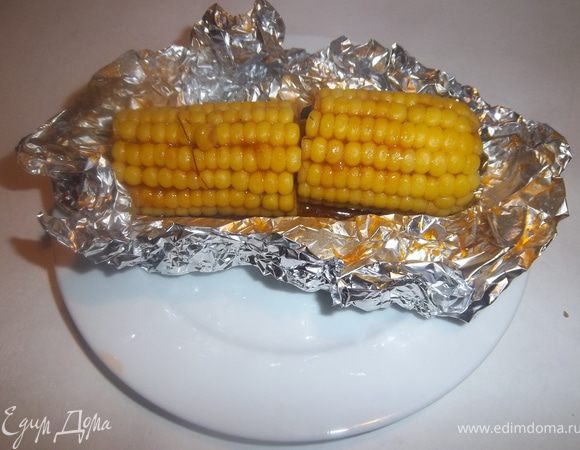 Вынуть кукурузу из фольги, положить на тарелку и полить образовавшейся при запекании соком.
