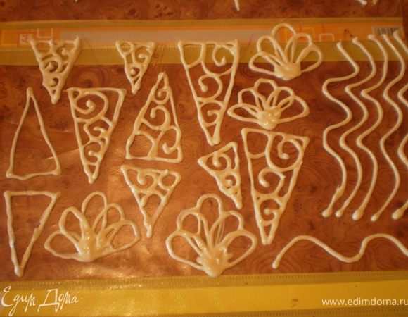 Делаем шоколадные украшения. Шоколад растапливаем на водяной бане или в микроволновке (в режиме разморозки, помешивая каждые 15-20 секунд). Из мешка отсаживаем на файлик нужные нам фигуры.