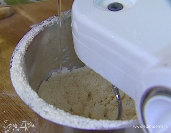 Когда масса приобретет консистенцию мелкой крошки, добавить 1 яйцо, желток и 80 мл ледяной воды и снова вымешать.
