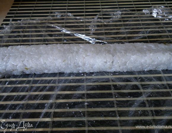 сворачиваем ролл с помощью бамбукового коврика, сворачиваем с той стороны, гда мы оставляли 2 сантиметра без риса