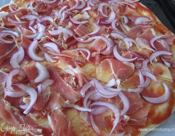 Утром тесто разровнять, придать ему круглую форму.
Тесто немного смазать кетчупом, выложить кусочки сыра, порезанное мясо, лук порезанный полукольцами.