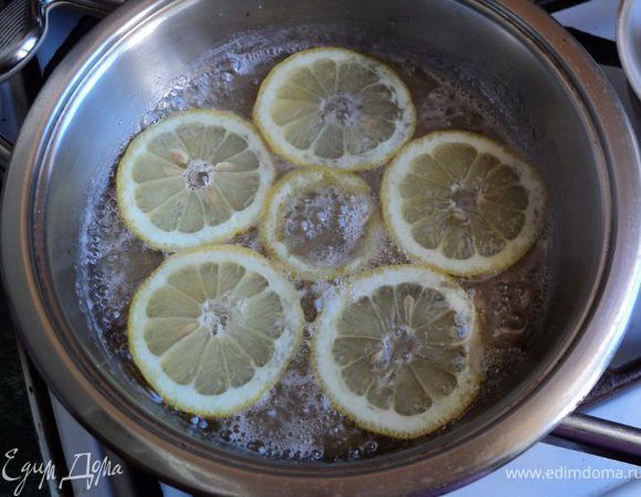 На сковороду положить 5ст. ложек сахара и немного воды, сварить сироп, в котором проварить по 3-4мин дольки лимона и апельсина. Готовые дольки выложить на сито, дать стечь сиропу, разрезать на половинки.