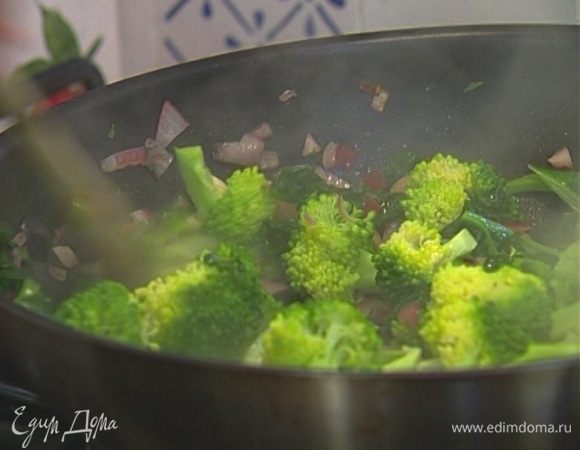 Через 2 минуты отправить в сковороду брокколи, влить сохраненную воду, в которой варилась брокколи, и прогревать на небольшом огне до готовности.