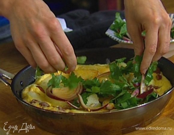 Присыпать картофель с колбасками 1 ч. ложкой листьев розмарина, влить в сковороду взбитые яйца и отправить в разогретую духовку на несколько минут. Подавать омлет, выложив на него лук с петрушкой.