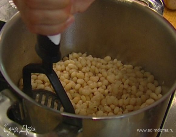 Жидкость слить в отдельную посуду, а фасоль слегка размять толкушкой, не превращая в пюре.