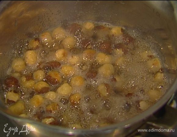 В небольшую кастрюлю влить 50 мл воды, добавить сахар и фундук, поставить на огонь и сварить карамель. 