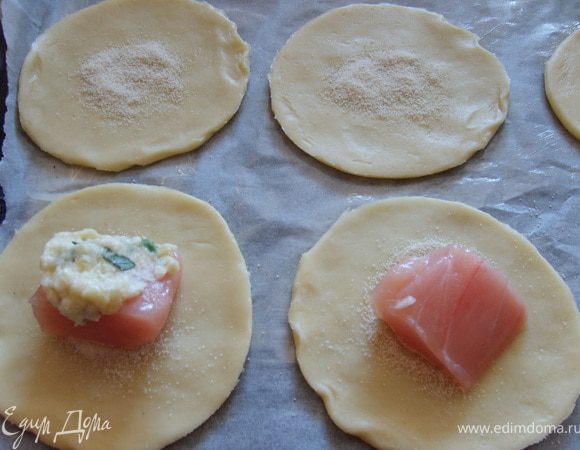 Теперь собираем наши пирожочки, на круг, что побольше сыплем совсем немного манки, кладем кусочек курочки и смазываем 1 ч.л. соуса