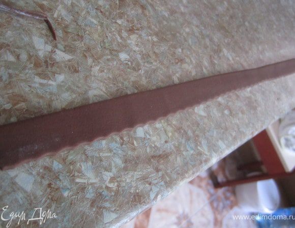 Из шоко-мастики скатать длинный жгутик, раскатать его и вырезать длинную полоску.