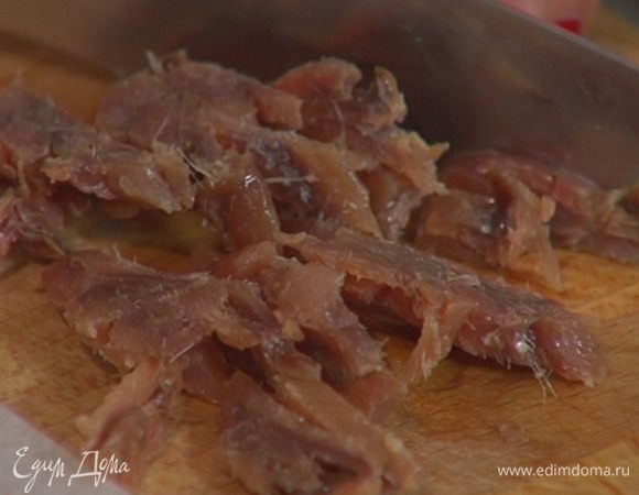 Измельчить 5–6 анчоусов, чеснок и половину листьев базилика, добавить все к луку и перемешать.