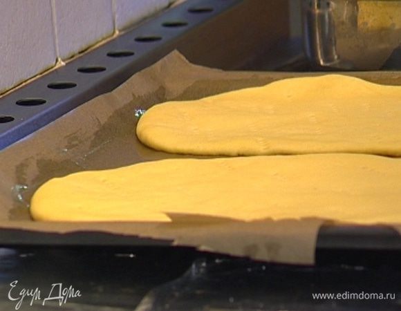 Большой прямоугольный противень смазать оставшимся сливочным маслом. Тесто разделить на 2 части, раскатать каждую в прямоугольный пласт, уложить на противень, накрыть полотенцем и оставить еще на 15 минут.