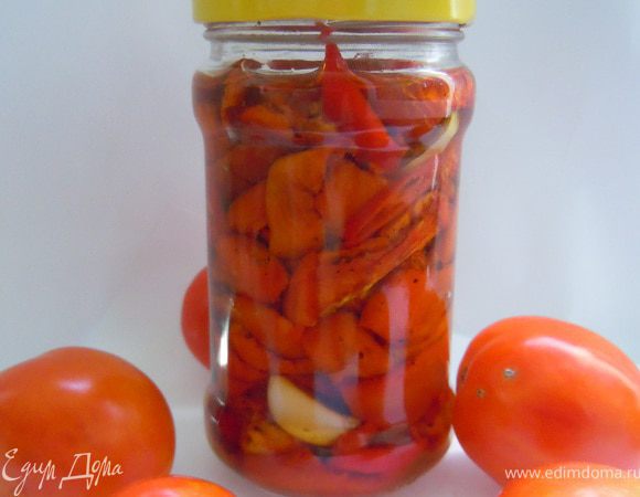 На дно  чистой банки  налить немного масла. Затем положить несколько зубчиков чеснока и немного нарезанного острого перца. Наполнить банку на 1/3 помидорами, влить еще немного масла, затем , помидоры и масло,положить еще немного чеснока и перца. Наполнить банку маслом.
Закрыть банки чистыми крышками и убрать на хранение в холодильник.