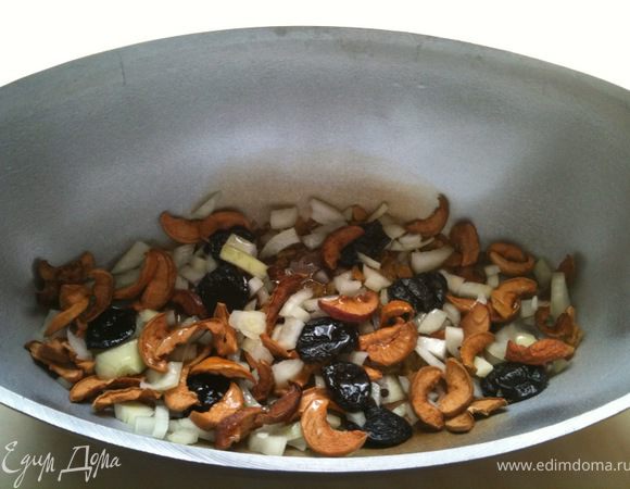 На дно гусятницы или казана положить 1/3 измельченного лука и 1/3 смеси сухофруктов.