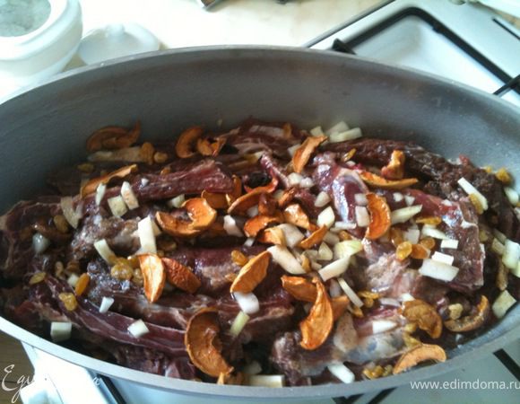 На подушку сухофруктов и лука плотно выложить слой ребер. Посолить, поперчить. Сверху снова повторить лук+сухофрукты.