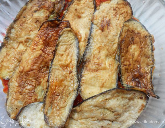 Духовку предварительно разогреть до 180С. Дно формы для запекания смазать томатным соусом, поверх вложить часть баклажанов. 