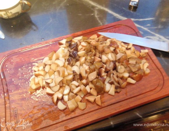 Отваренные грибы довольно мелко режем. И отправляем сначала на сухую сковороду, когда лишняя влага уйдет, добавляем масло и половину нашинкованного лука. Обжариваем до золотистости.
