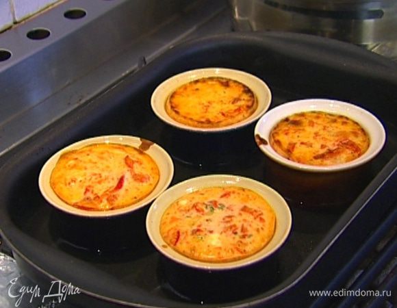 Поместить формы в глубокий противень, наполнить его горячей водой и выпекать чизкейки в разогретой духовке 20−25 минут, затем остудить.