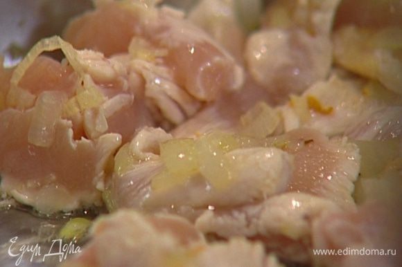 Куриные грудки нарезать длинными тонкими полосками, выложить в сковороду к луку с чесноком и, помешивая, обжаривать в течение 2−3 минут.