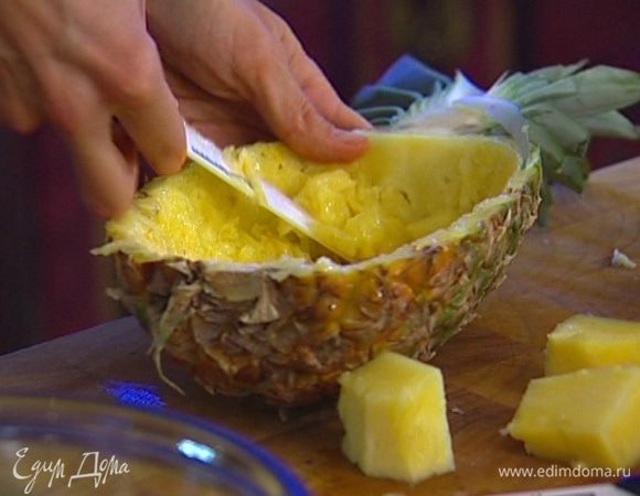 Ананас поставить вертикально и разрезать его пополам, начиная с макушки, надрезать в каждой половинке мякоть квадратиками и вынуть ее. 