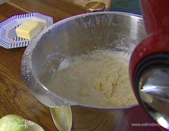 Приготовит тесто: нарезать кубиками 80 г предварительно охлажденного сливочного масла и выложить в чашу комбайна, всыпать оставшуюся муку, сахар, 1 ч. ложку соли и вымешать насадкой-венчиком.