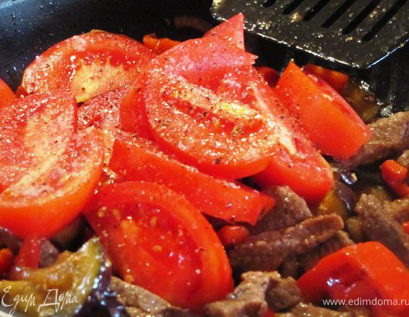 Через 3-5 минут добавляем нарезанный дольками помидор, дополнительно перчим, солим и перемешиваем.