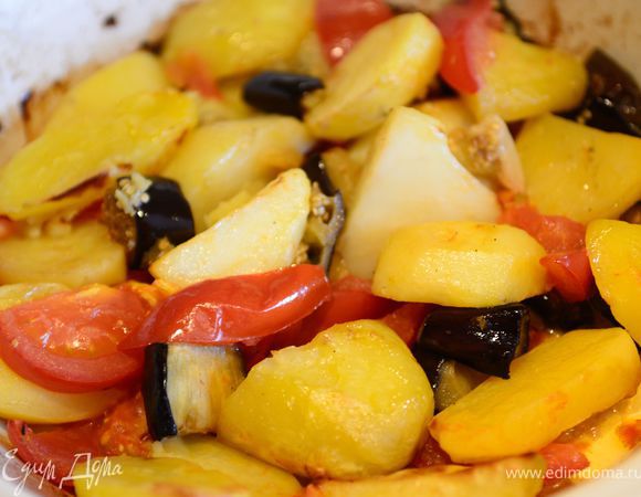 Раздавить и порезать крупно чеснок, залить его оливковым маслом, и вылить в форму с картофелем и баклажанами, добавить соль, перец, хорошо перемешать. Выпекать 20 минут. Один раз перемешать, добавить порезанные дольками помидоры и выпекать еще 15-20 минут.