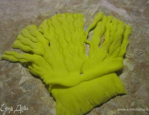 Для волос, раскатать кусочек желтой мастики, фигурным ножом прокатать по мастике, немного нажимая и делая нажрезы на кончиках.