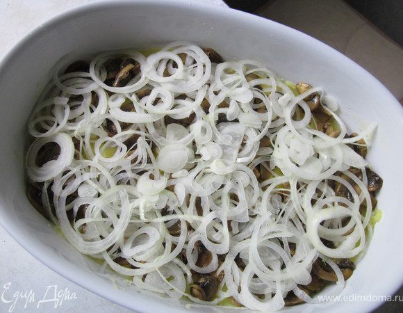 Лук нарезать тонкими колечками и разложить на грибы. Поверх лука выложить еще часть картофельного пюре.