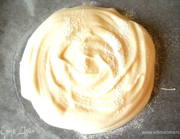 Затем, взбивая, понемногу добавлять сахарную пудру. Когда масса станет блестящей и эластичной добавить крахмал и лимонный сок, осторожно вмешивая. Духовку разогреть до 130 градусов. На бумаге для выпечки нарисовать круг диаметром 20 см, осторожно распределить белковую массу.  