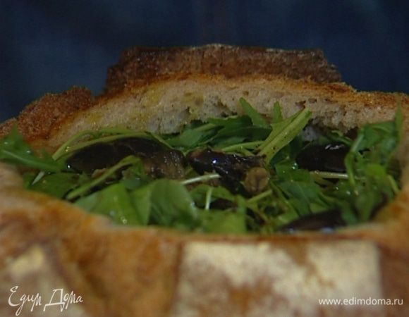 Выложить дно и стенки внутри хлеба салями, затем уложить слой моцареллы, сверху — вяленые помидоры, затем ветчину, руколу и половинки оливок (каждый слой придавить, слегка посолить и поперчить).