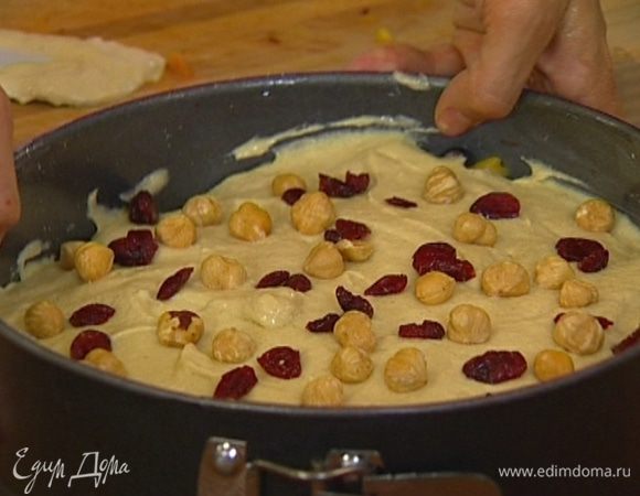 Выложить на фрукты с орехами тесто, присыпать оставшимися дроблеными и целыми орехами и клюквой.