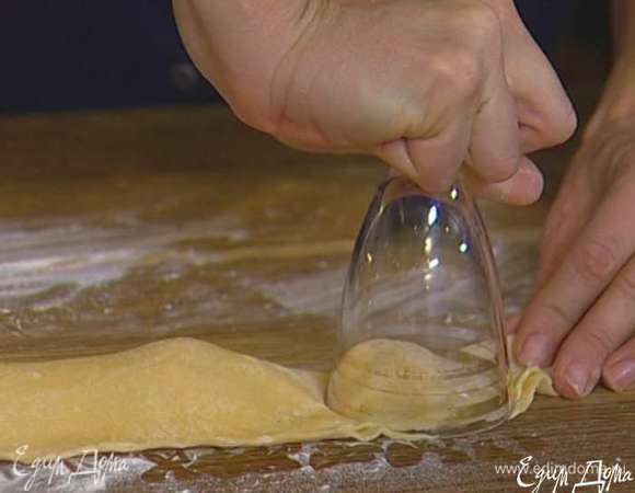 Раскатать тесто в тонкий пласт толщиной 1−2 мм, стаканом или чашкой вырезать кружки, положить в центр каждого начинку и защипнуть края.