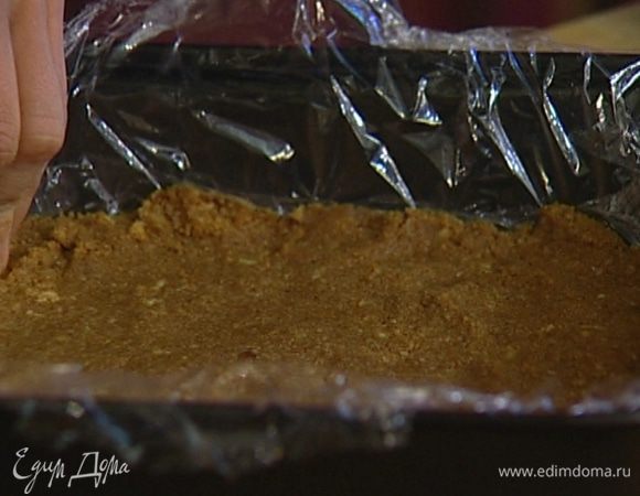 Выстелить форму пищевой пленкой и выложить в нее получившуюся массу, прижимая пальцами, чтобы корж был ровным. Отправить в холодильник на 30 минут.