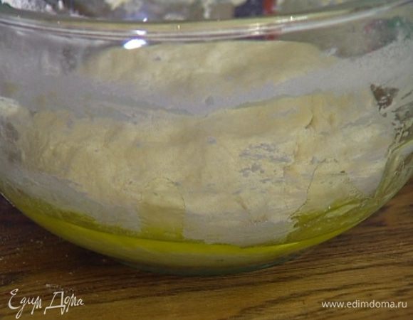 Выложить тесто на рабочую поверхность, присыпанную мукой, и слегка вымесить, затем уложить снова в посуду, смазанную оливковым маслом, накрыть влажным полотенцем и оставить еще на 10 минут.