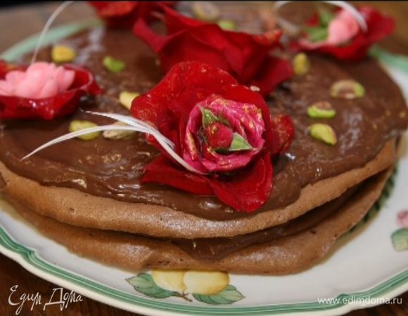 Смазать остывшие меренги шоколадным кремом, уложить одну на другую и украсить сверху, например, живыми красными розами, и присыпать фисташками.