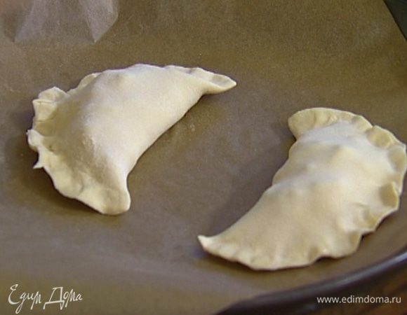 На одну половину раскатанного пласта выложить начинку, накрыть второй половиной теста, прихватить края. Так же сделать второй пирожок. 