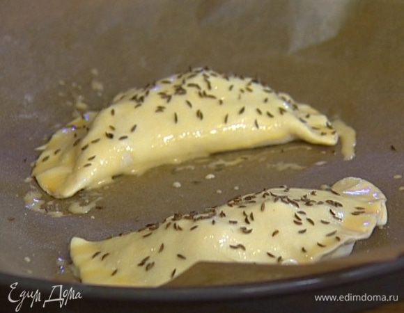 Желток смешать с молоком и смазать поверхность пирожков этой смесью, затем присыпать тмином и выпекать в разогретой духовке до готовности теста 20–25 минут.