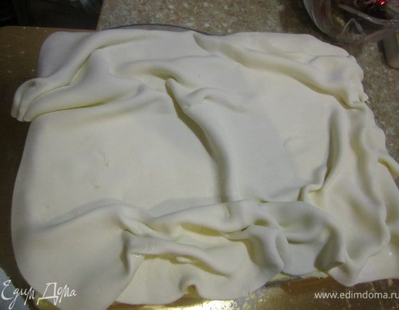 Белую мастику раскатать, уложить на торт.