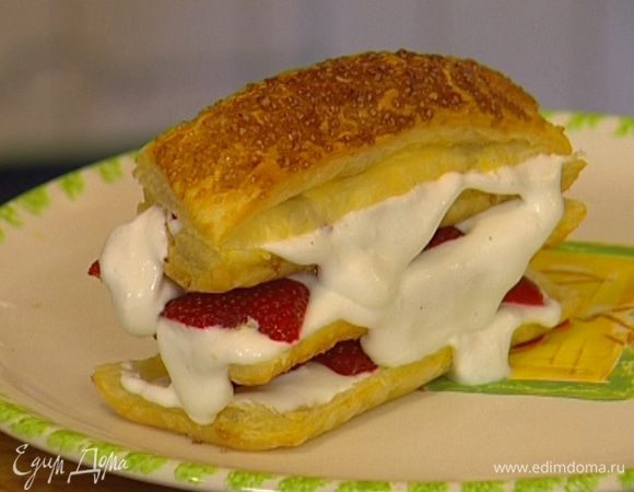 Смазать одну полоску взбитыми сливками, выложить сверху немного клубники, накрыть тестом, затем снова слой сливок, клубники и теста — для каждого пирожного понадобятся 4 разрезанные полоски. Верхний слой теста не смазывать сливками, а только присыпать сахарной пудрой.