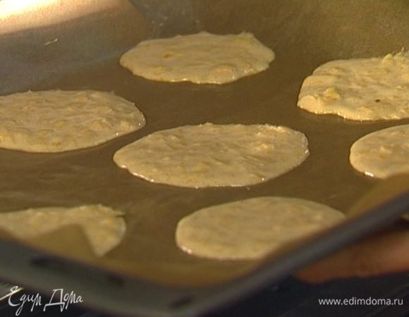 Смазать сливочным маслом бумагу для выпечки и ложкой выложить на бумагу небольшие тонкие лепешки.