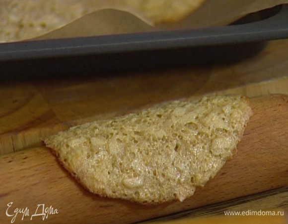 Выпекать в разогретой духовке 6–8 минут, затем горячие печенья уложить на скалку, чтобы они, застывая, приобрели изогнутую форму. 