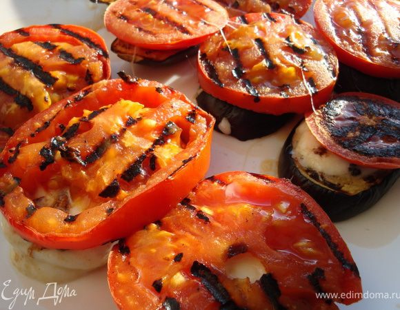 Собираем башенки дальше: на баклажаны с сыром раскладываем помидоры и присыпаем базиликом. Теперь все это дело слегка сбрызгиваем оливковым маслом. Можно дать блюду немного постоять, чтобы овощи с сыром пропитались друг другом, а если уже не терпится, то смело выставляйте на стол и налетайте. Не забудьте поделиться с ближними, это очень вкусно. Приятного аппетита!
P.S. Можно еще сначала потереть зубчиком чеснока горячие баклажаны, а потом собрать башенки.