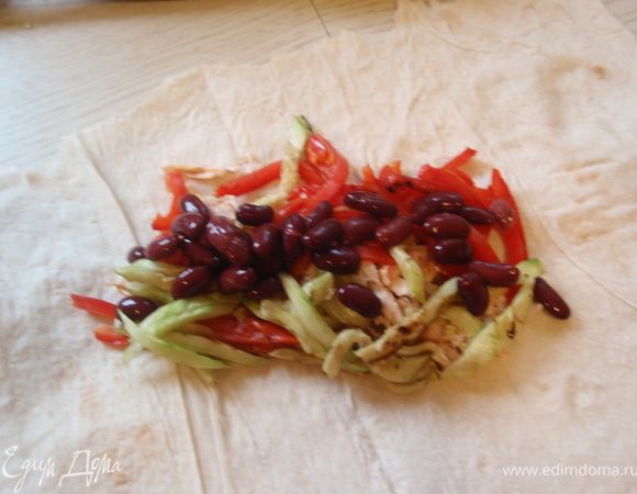 Тартилью можно приготовить самим по одному из рецептов с нашего сайте например рецепт от Станислава http://www.edimdoma.ru/recipes/17351 или от olgalina http://www.edimdoma.ru/recipes/14823 Но мне кажется, что и лаваш тут прекрасно подходит. На лаваш равномерно укладываем курицу и овощи гриль. Фасоль промыть от маринада и выложить сверху.