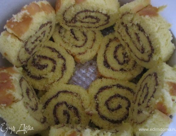 Дно разъемной формы покрыть пищевой пленкой, бока пергаментной бумагой.
Выложить кусочки рулета.