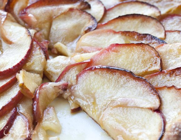 Ломтики яблок веером уложить на тесто, сверху разложить оставшееся масло, присыпать оставшимся сахаром и корицей.
